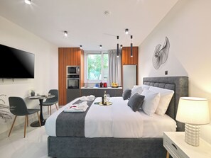 Ein modernes Hotelzimmer mit einem großen Bett, einem Flachbildfernseher, einem Essbereich und Blick ins Freie.