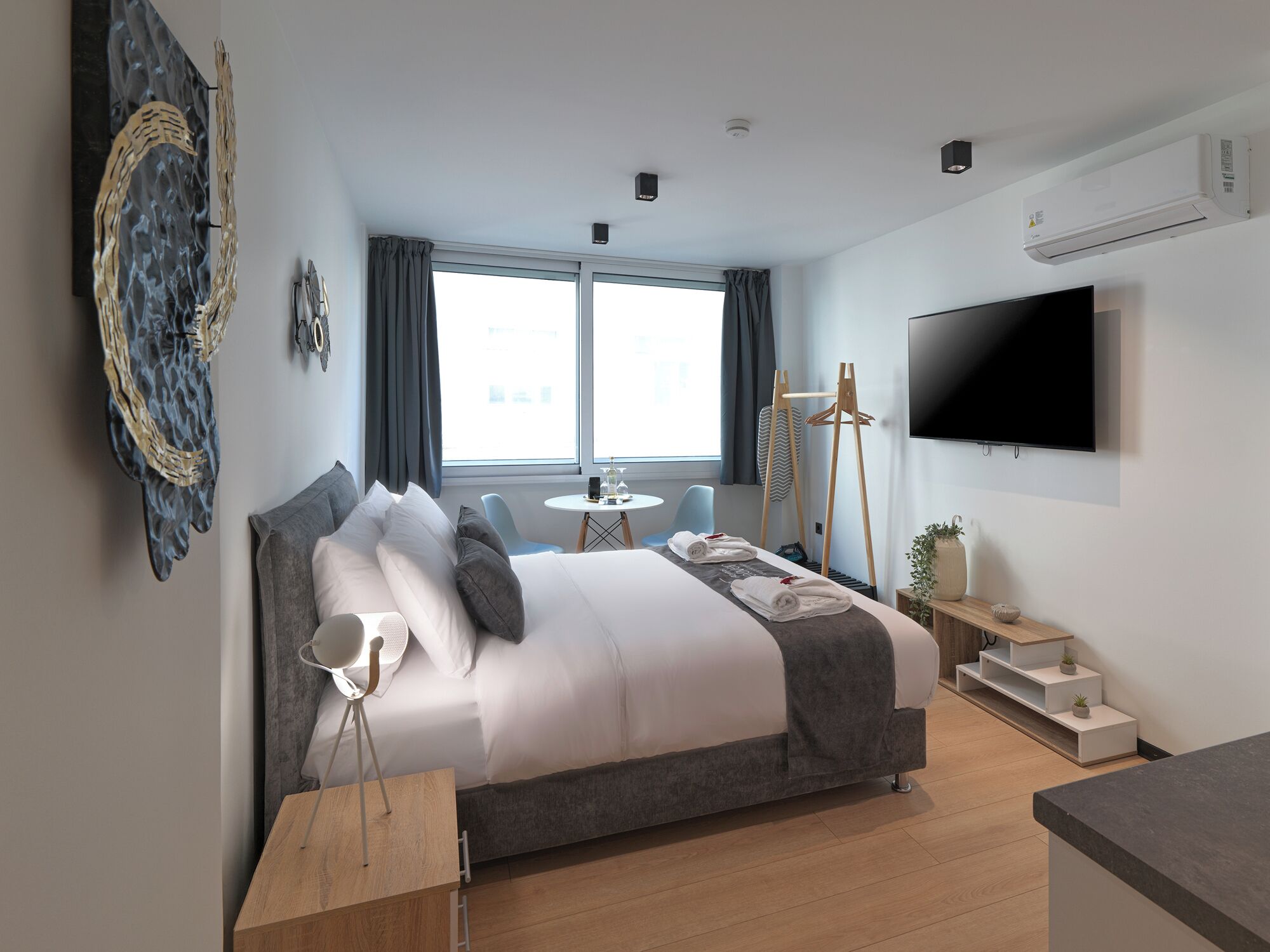 Ett modernt hotellrum med en stor säng, en platt-TV, ett skrivbord och ett fönster med gardiner.