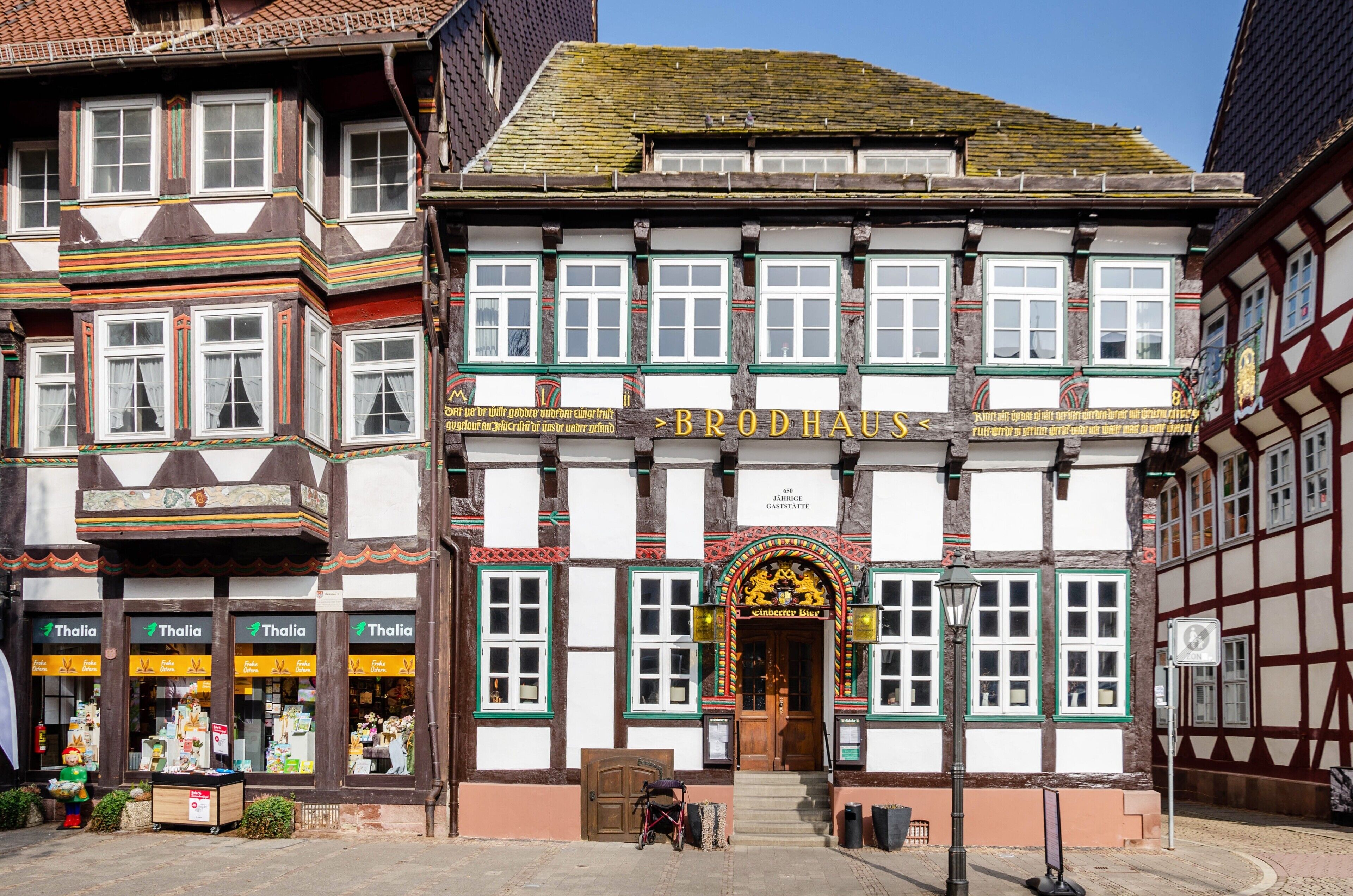 Un bâtiment traditionnel à colombages, sur lequel on peut lire l’inscription « Brodhaus », et un magasin, dont l’enseigne « Thalia » est affichée au rez-de-chaussée.