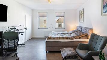 A bedroom with a bed, a chair, a desk, and a radiator.