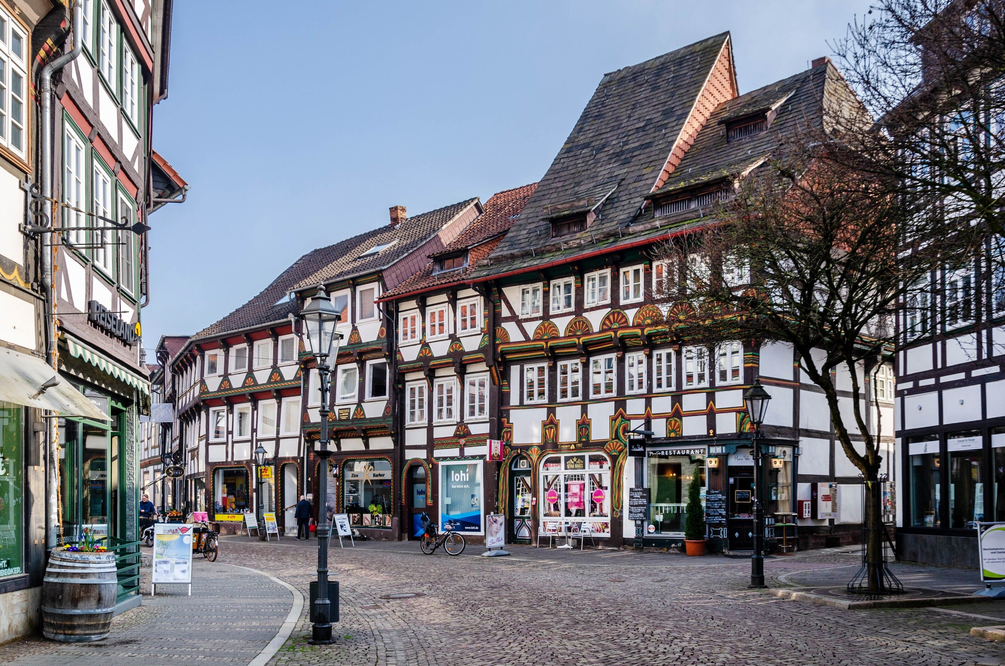 A traditional European street with half-timbered buildings, cobblestone pavement, and a clear sky.