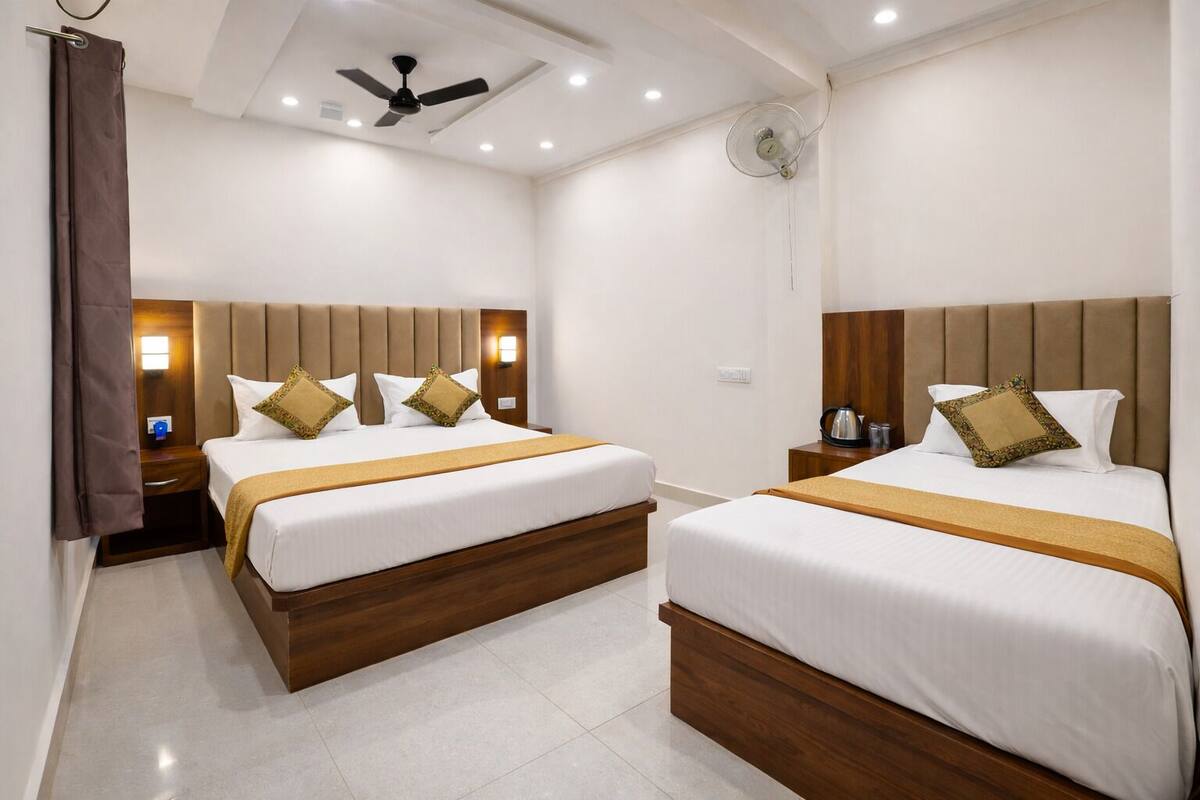 A hotel room with two beds, wooden headboards, white bedding, and a ceiling fan.