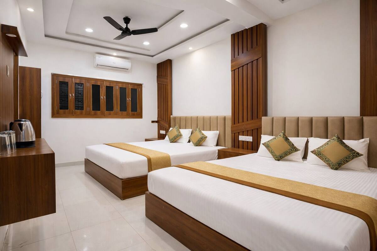 A hotel room with two beds, a ceiling fan, and a coffee maker on a wooden table.