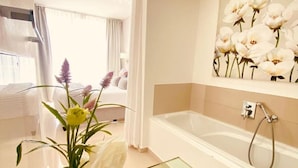 Et moderne badeværelse med et bord-arrangement i glas, badekar og et vægmonteret brusebad.