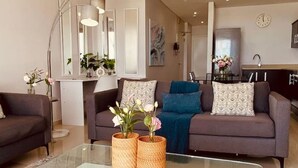 En moderne stue med et glasbord, to sofaer og et spiseområde i baggrunden.