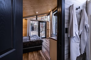 Een moderne slaapkamer met een houten plafond, een groot bed en uitzicht op de omgeving door een schuifdeur.