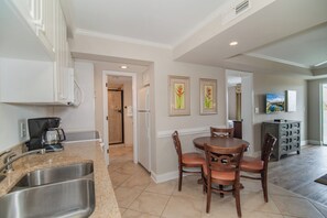 A kitchen with a coffee maker, a sink, and a dining area with chairs and a table. - SH 322 1BR Condo Pond View, Lazy River, Hot Tubs & Beach Access LBTS (Pawleys Island)