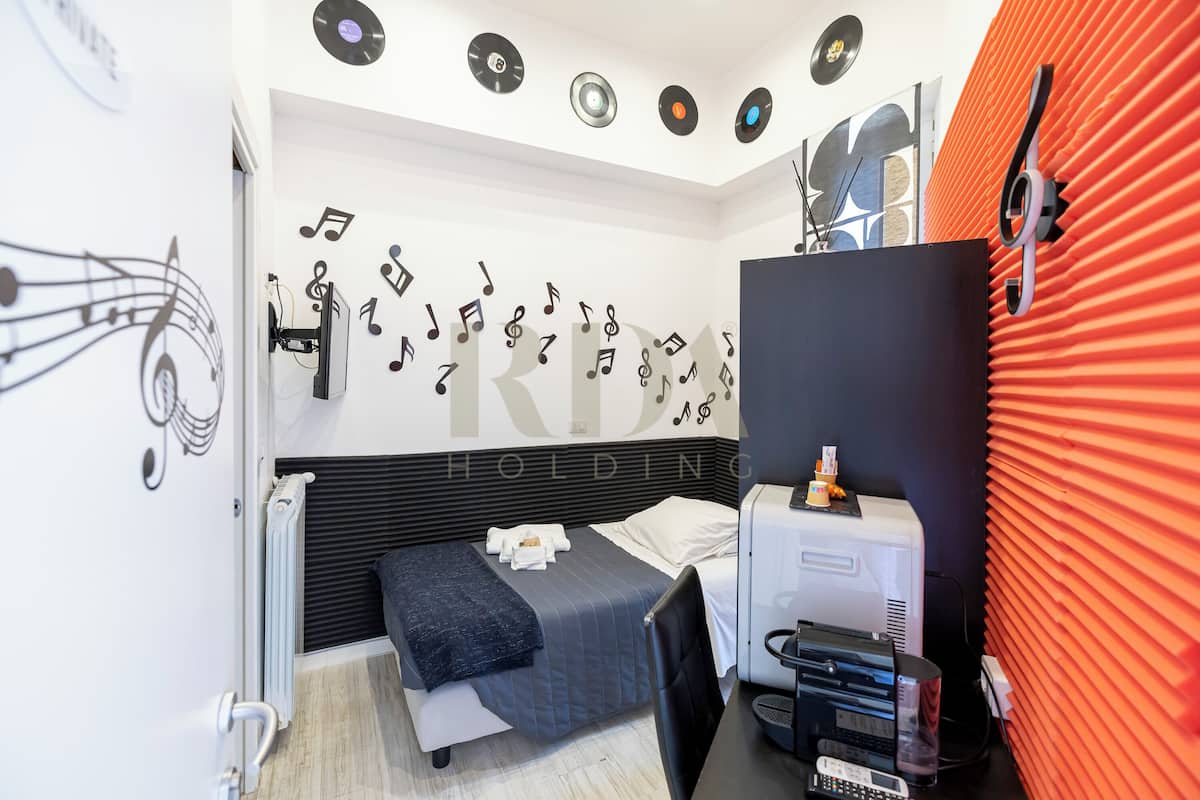 Une chambre d’hôtel moderne équipée d’un lit, d’un bureau et d’un panneau acoustique rouge.
