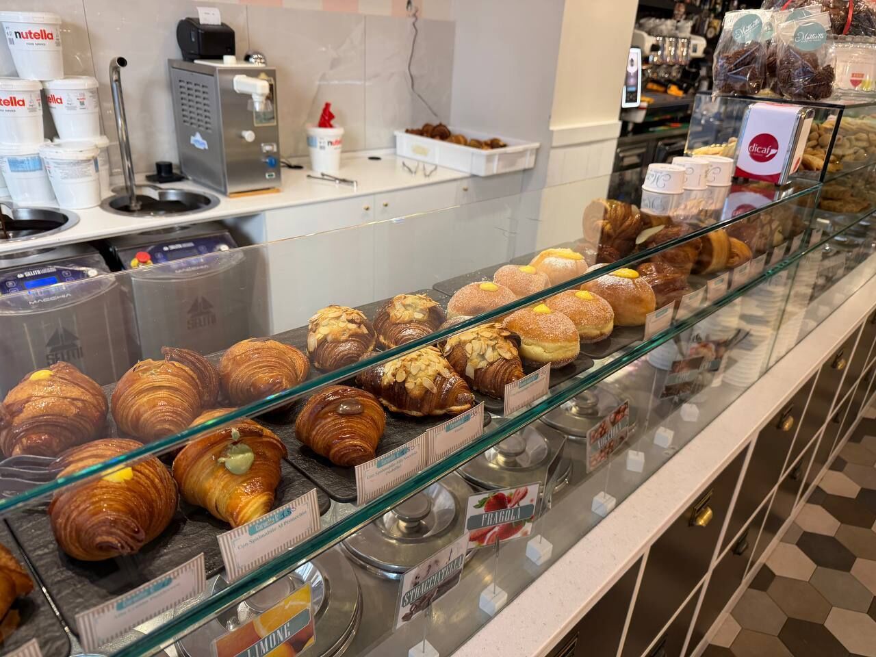 Una vetrina di pasticceria con diversi dolci e una macchina per caffè.