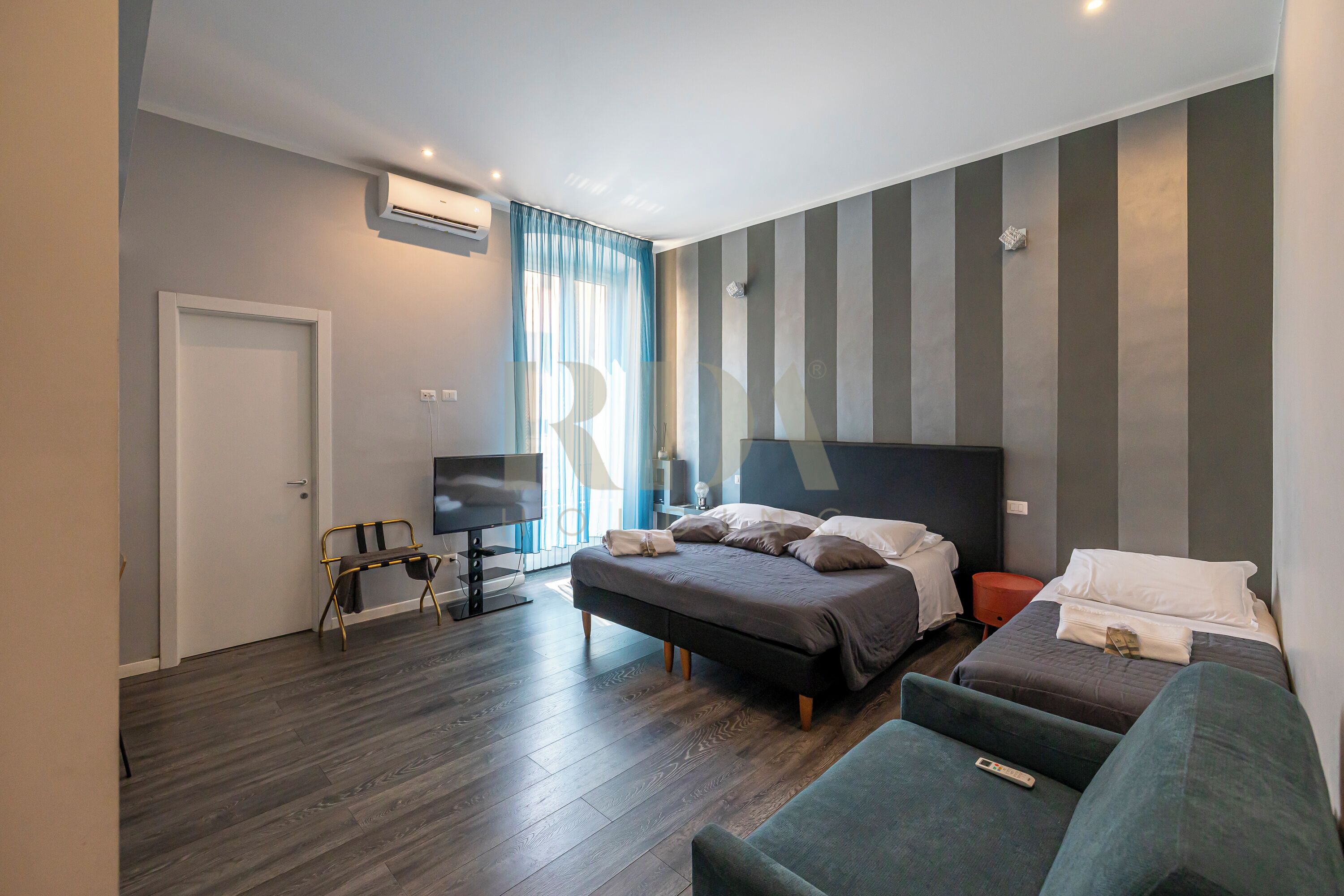 Een moderne hotelkamer met een groot bed, een televisie, een bureau en een bank.