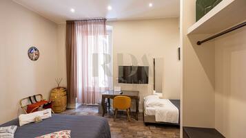 Ein Hotelzimmer mit Bett, Schreibtisch, Stuhl, Fernseher und Kleiderschrank.