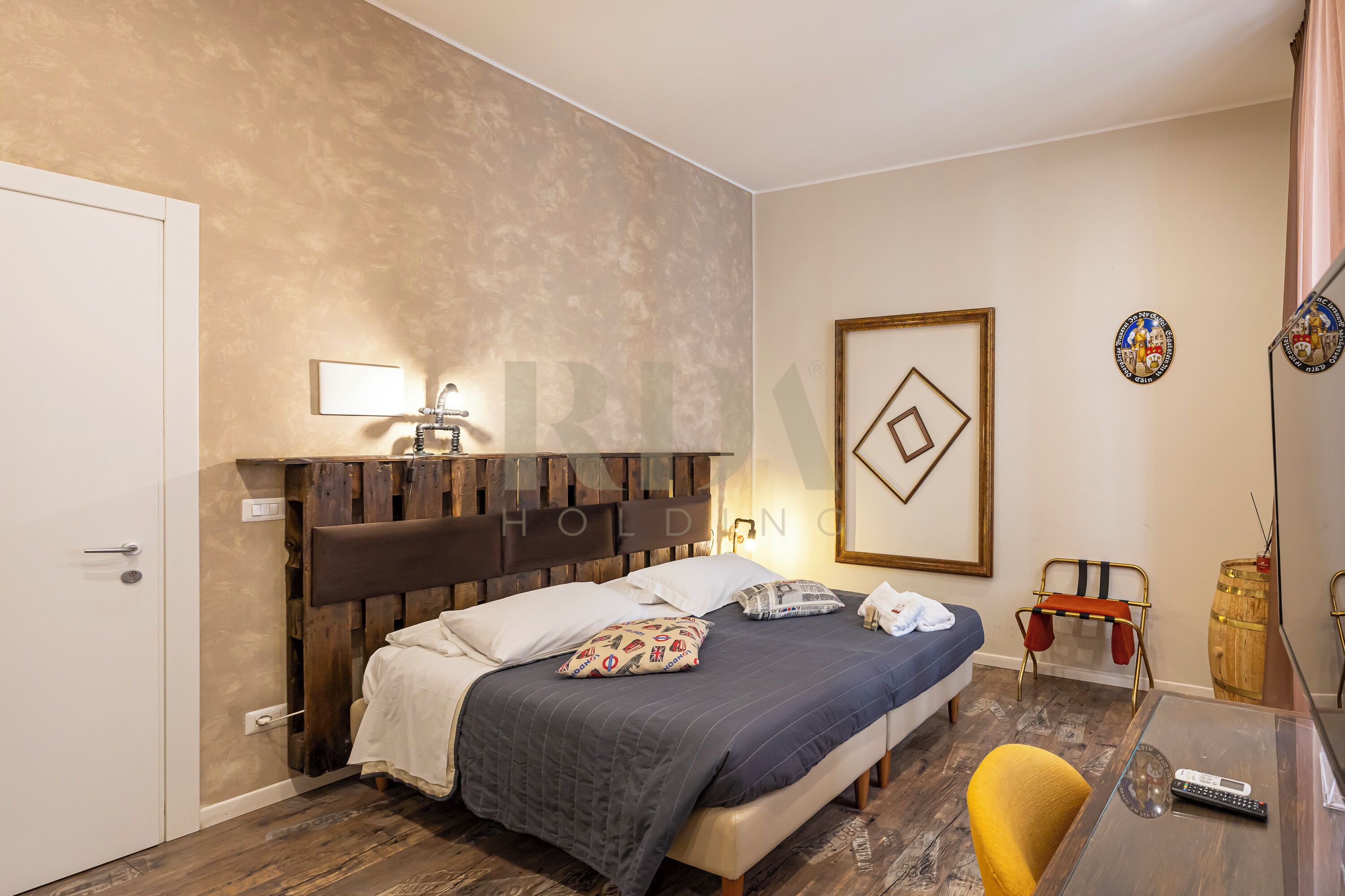 Ein Schlafzimmer mit einem Bett, einem Nachttisch, einer Lampe und einem Sessel.