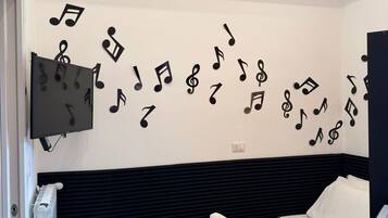 Ein Schlafzimmer mit einem Bett, einem Flachbildfernseher und Wanddekorationen, darunter Schallplatten und Noten.