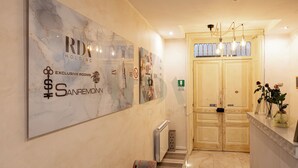 A hotel hallway with a marble wall, a reception desk, and a double door. - SanremoInn Exclusive rooms (Sanremo)