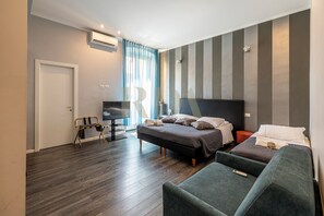 A modern hotel room with a large bed, a sofa, a TV, and a desk. - SanremoInn Exclusive rooms (Sanremo)