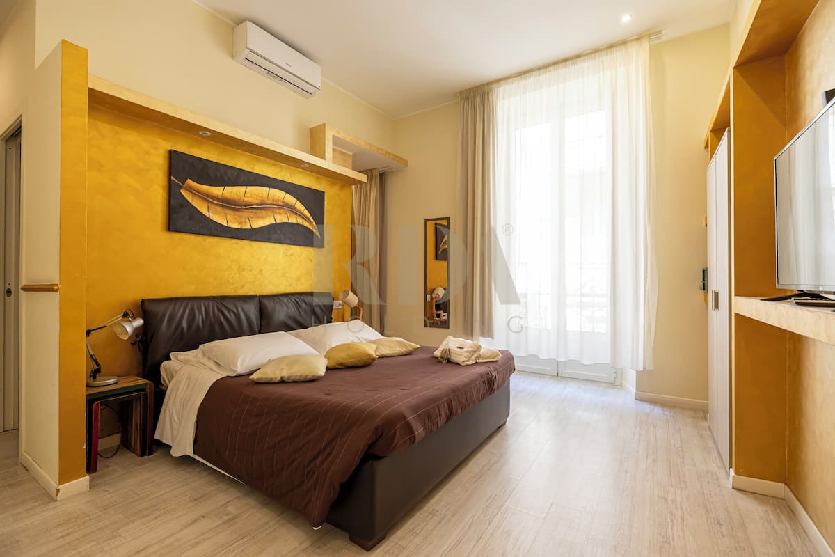 Une chambre à coucher avec un lit, des tables de chevet, un miroir et un tableau accroché au mur.