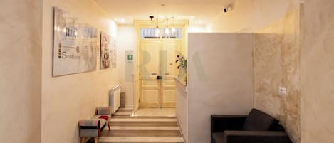A hallway with a wooden floor, a bench, a sofa, and a door leading to a room.