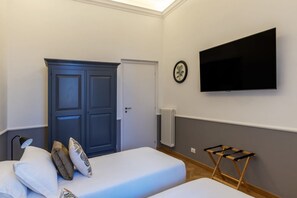 A bedroom with two beds, a wardrobe, a TV, and a radiator. - Castro Pretorio 25 - FHTR (Roma)