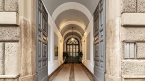 Un couloir doté de plafonds en arc de cercle et de portes à deux battants, qui mène à une pièce avec une grande fenêtre et une porte.