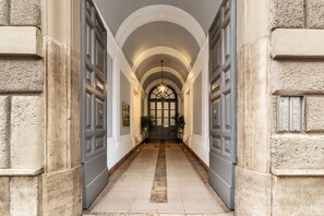 Ein Korridor mit tonnenhohen Decken und doppelten Türen, der zu einem Raum mit einem großen Fenster und einer Tür führt.