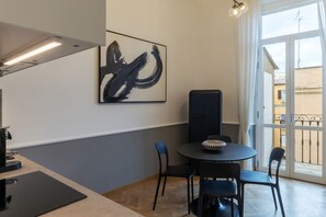 Ein Zimmer mit Esstisch, Stühlen, einem schwarzen Lautsprecher und einem großen abstrakten Gemälde an der Wand.