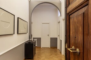 Ein Flur mit Holzboden, weißen Wänden, einem schwarzen Schrank und einer Holztür.