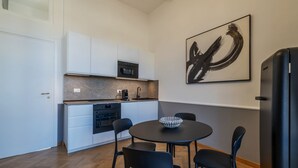 Une cuisine moderne avec des meubles blancs, un plan de travail noir et un saladier noir et blanc posé sur une table ronde.