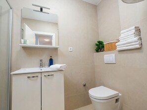 A modern bathroom with a white sink, mirror, and toilet. There are towels and toiletries on the sink. - Two-bedroom family room apartment Casa Del Mar 1 with terrace (Stara Novalja)