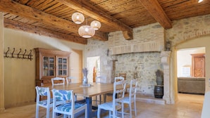 A dining area with a wooden table and chairs, a stone wall, and a wooden ceiling. - Guest Room “Côté Cour” with Large Shared Courtyard and Wi-Fi (Saint-Remèze)