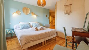A bedroom with a bed, bedside table, chair, wooden floor, and a hanging light fixture. - Guest Room “Côté Cour” with Large Shared Courtyard and Wi-Fi (Saint-Remèze)