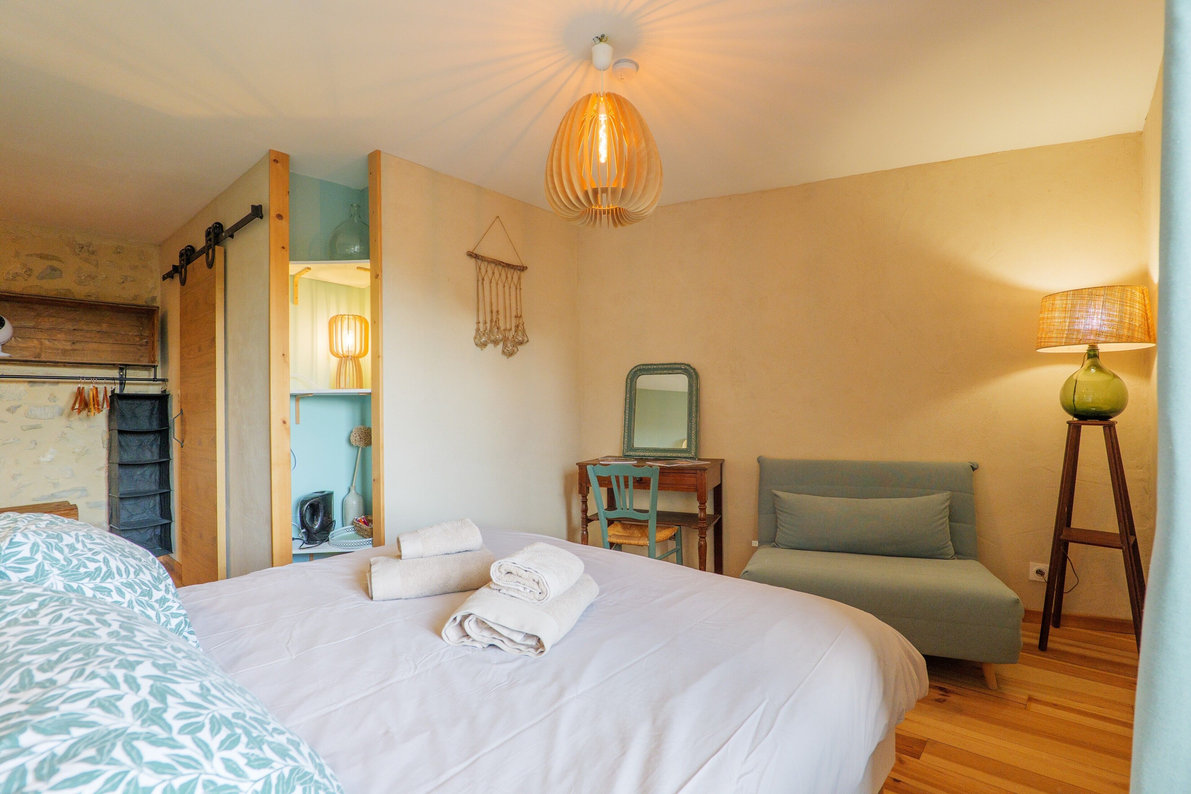 Ein Schlafzimmer mit Bett, Stuhl, Schreibtisch, Spiegel und Lampe.