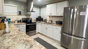A modern kitchen with white cabinets, stainless steel appliances, and granite countertops. - Houston Home Near NRG Sleeps 6 (Houston)