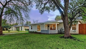 A single-story house with a front porch, a small front yard, and a wooden fence. - Houston Home Near NRG Sleeps 6 (Houston)
