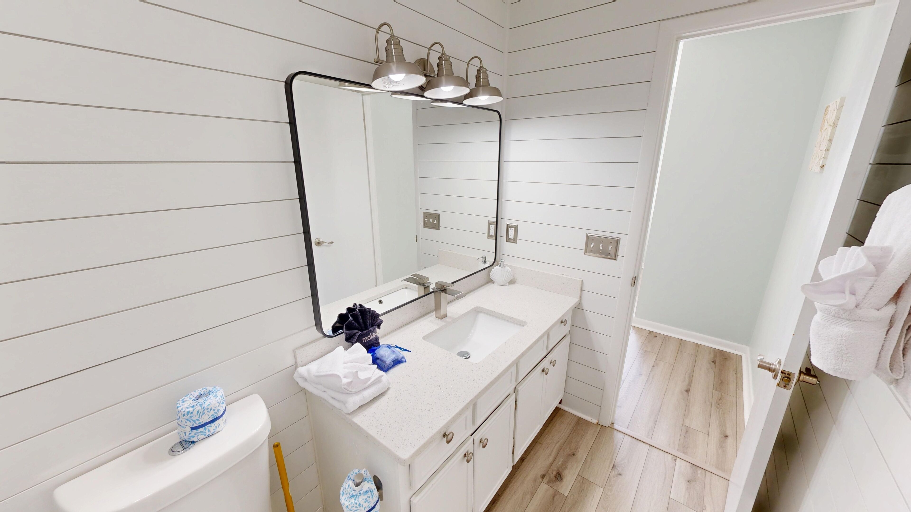 A bathroom with a white vanity, a large mirror, and a sink.