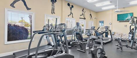 A gym with various exercise equipment, including treadmills and stationary bikes, and motivational wall art.