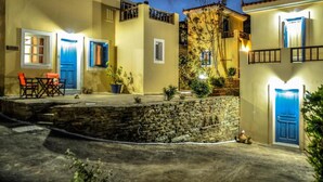 Un cortile con mura in pietra, una porta blu e un piccolo spazio relax con sedie.