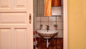 Un bagno con una porta bianca, un lavandino con un rubinetto e un portasciugamani.