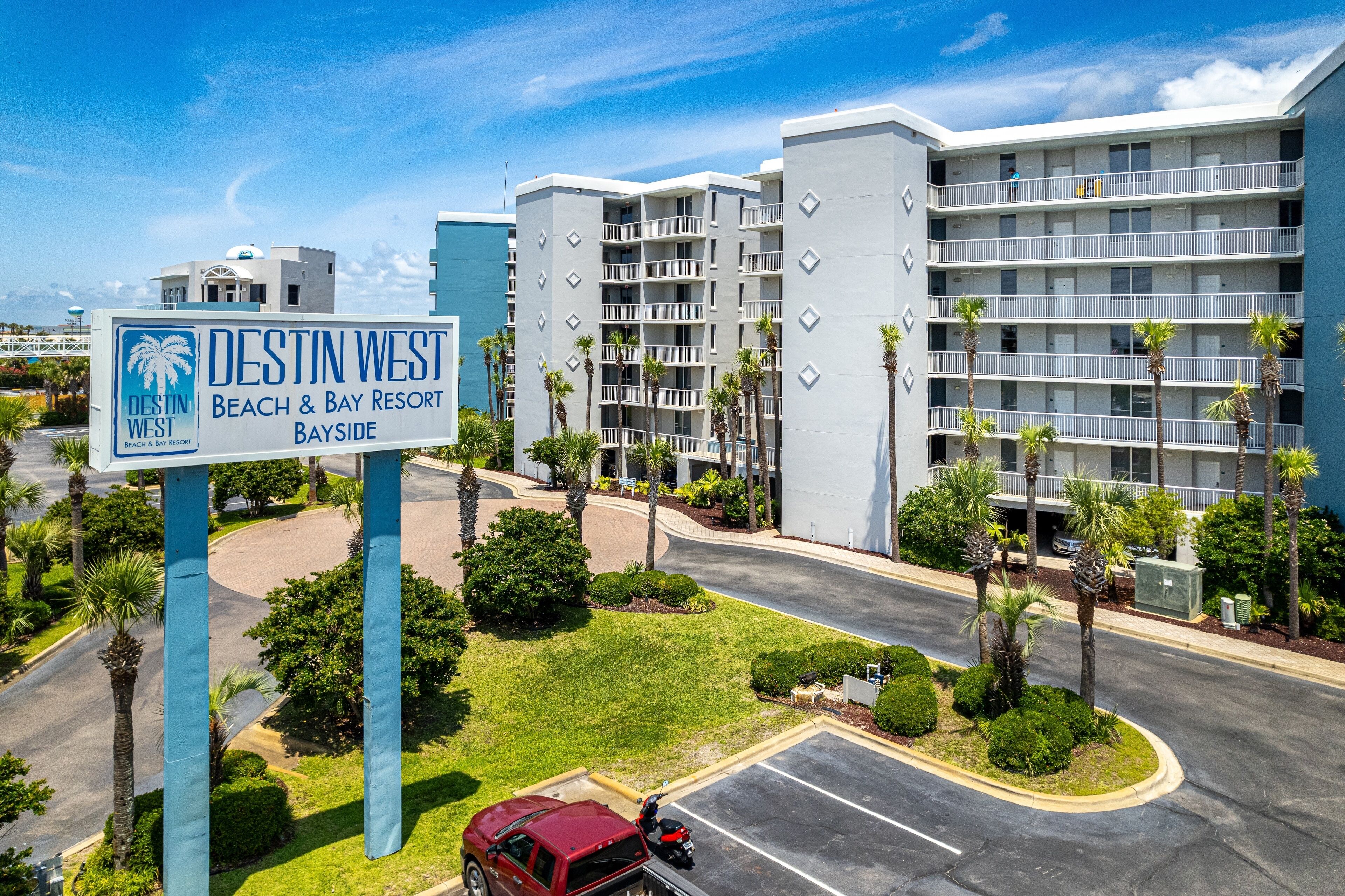 Un complexe hôtelier avec une enseigne indiquant « DESTIN WEST, complexe hôtelier en bord de mer et sur la baie, côté Bayside ».