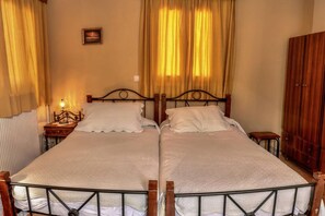A double bed with a metal frame, two bedside tables, a nightstand, and a wooden wardrobe. - Mainades Maisonette - Kalibia Seaview Retreat (Menites)