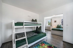 A bunk bed with green bedding, a ladder, and pillows. There is a window with a view of the outdoors. - Apartment 'Ferienwohnung Zum Schwarzwaldfrosch' with Balcony and Wi-Fi (Freudenstadt)