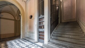 A grand staircase with a checkered floor leading to a door with a metal gate. - Vista Lumina by MMega (Florence)