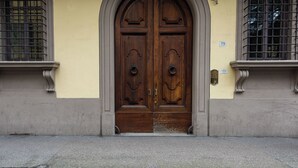 A double wooden door with a decorative arch above it, set in a building with a light yellow facade. - Vista Lumina by MMega (Florence)