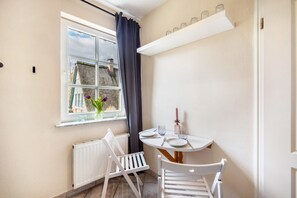 A small room with a window, a table with chairs, a radiator, and a shelf with jars. - Apartment 'Niemark Gestüt Kriseby' with Shared Terrace and Wi-Fi (Lübeck)