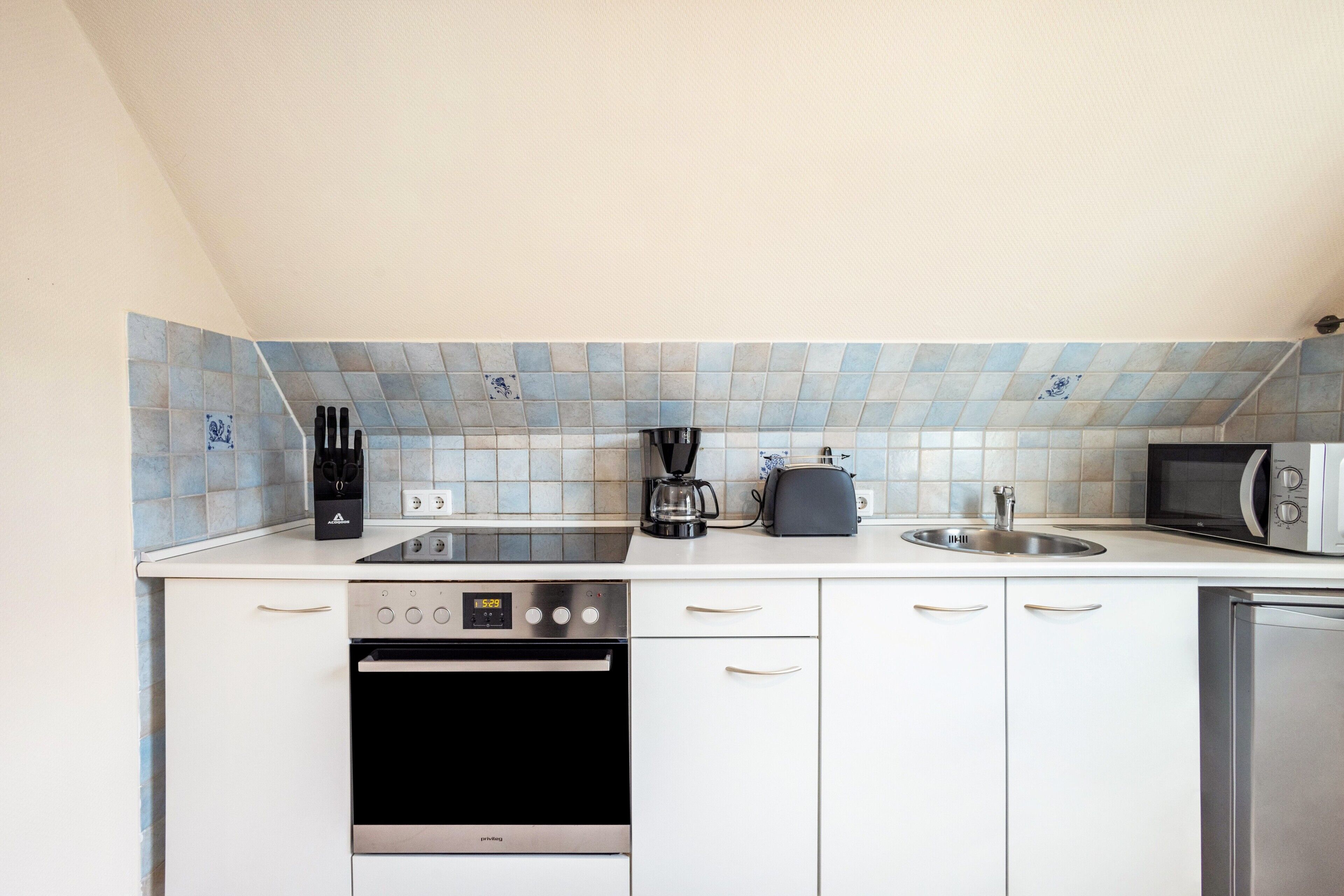 Eine kleine Küche mit Mikrowelle, Toaster, Kaffeemaschine und Backofen.