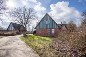 A residential house with a sloped roof, a brick facade, and a paved driveway. - Apartment 'Niemark Gestüt Kriseby' with Shared Terrace and Wi-Fi (Lübeck)