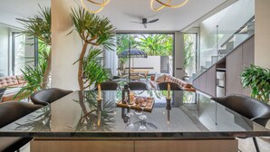 A modern dining area with a glass table, black chairs, and candles. There are potted plants and a view of the outdoors. - Pera Villa Ubud Bali. (Ubud)
