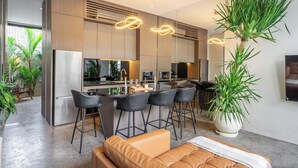 A modern kitchen with a central island, bar stools, and a large potted plant. - Pera Villa Ubud Bali. (Ubud)