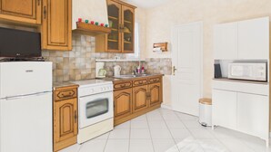 A kitchen with wooden cabinets, a white refrigerator, a stove, a microwave, and a coffee maker. - House for 5 with garden, beach 500m away (Saint-Hilaire-de-Riez)