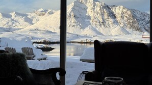 Una habitación con vistas a montañas nevadas y a un lago.