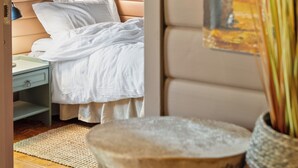 Un dormitorio con cama, mesita de noche, lámpara y un cuadro en la pared.